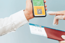 Pessoa mostrando um celular com um QR code para um agente que segura um passaporte e um cartão de embarque, durante um procedimento de checagem de viagem